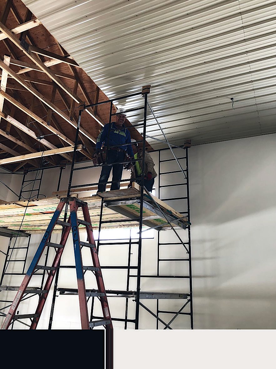 RELCO tradesman working from scaffold beneath exposed roof framing