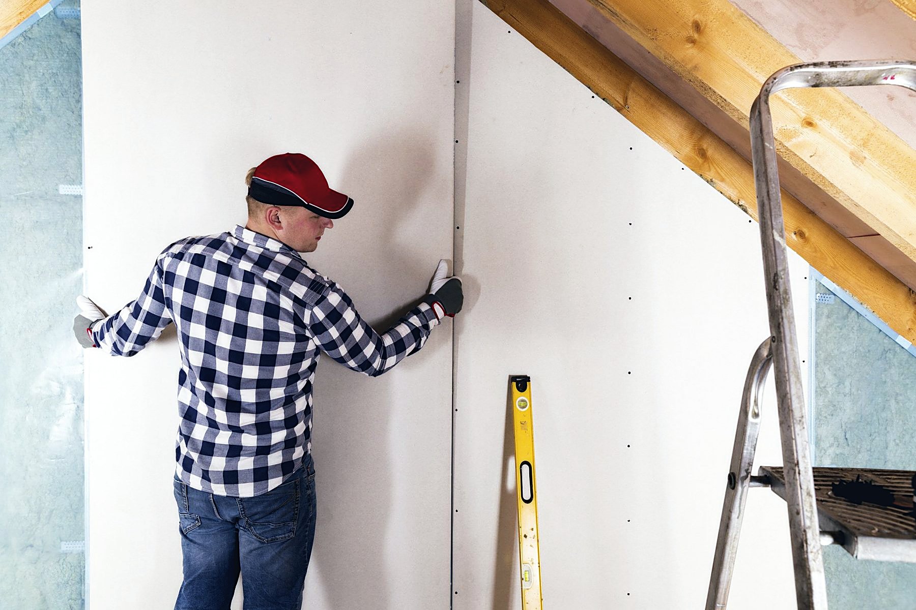 Tradesman setting a sheet of drywall