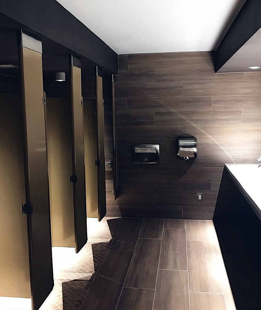 Upscale commercial restroom with wood-look tile and partitions